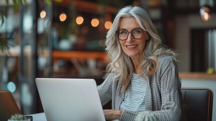 A smiling middle-aged businesswoman sits confidently at the table. The laptop is open in front of you. This is a testament to the power of technology. Bringing people together to achieve shared goals - Powered by Adobe