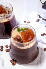 Cold Brew Coffee Espresso Carajillo Cocktail with frozen espresso ice cubes, strong black coffee, liqueur and Vodka, on white kitchen table background copy space