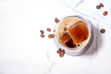 Cold Brew Coffee Espresso Carajillo Cocktail with frozen espresso ice cubes, strong black coffee, liqueur and Vodka, on white kitchen table background copy space