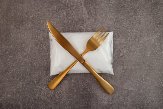 White powder with chemical formula NaNO2. Sodium nitrite or preservative E250 in plastic bag. Golden fork and knife symbolize the prohibition or refusal to use dangerous food additives with E number