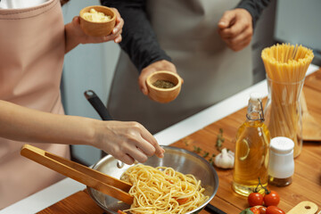 Close up of hand couple chef influencers cooking spaghetti mix ingredient taking to frying pan,...