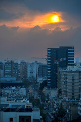 Sunset over the sea in the city of Herzliya, with buildings and construction cranes.
