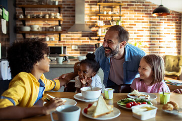 Multiracial children sharing a joyful moment with father at kitchen table
