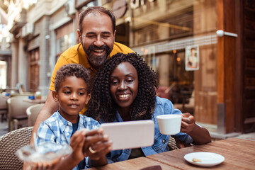 Happy multiracial family taking a selfie at an outdoor cafe