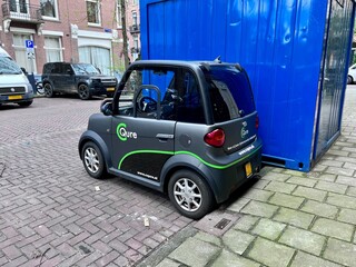 Urban Mobility in Amsterdam: A compact electric car parked on a cobbled street in Amsterdam, showcasing sustainable urban transport solutions in a typical European city setting.