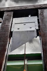 Guillotine under a sky of storm clouds