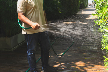 Man watering plant in the garden with hose.