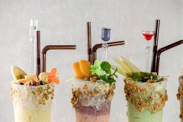 Three glasses of fruit smoothies with straws and fruit decorations.