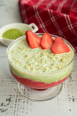 Tasty matcha oatmeal and strawberries in serving glass. Healthy breakfast