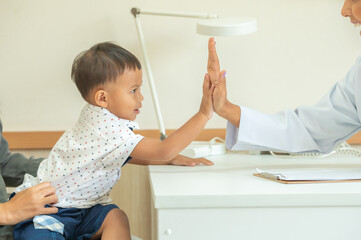 Pediatrician giving a young boy a high five during a checkup