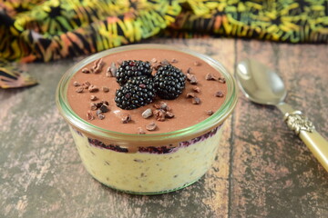 Overnight oatmeal with mashed blackberry and chocolate cream, on top garnish with fresh blackberry and cacao nibs