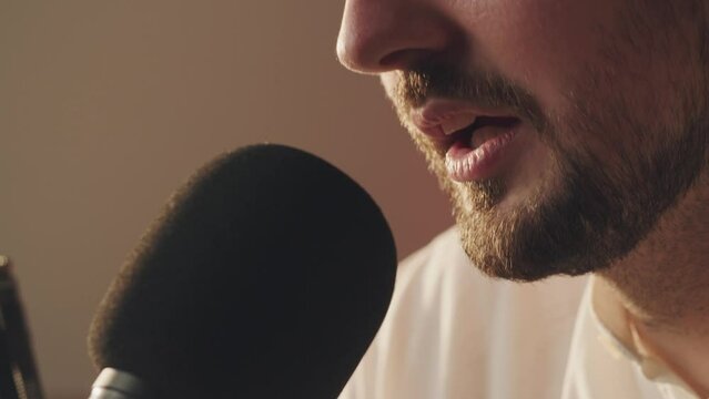 Close up podcaster guy speaking into microphone bad news for american citizens. Radio broadcaster man recording podcast. Bearded blogger speaks in mic. Backstage of recording interview