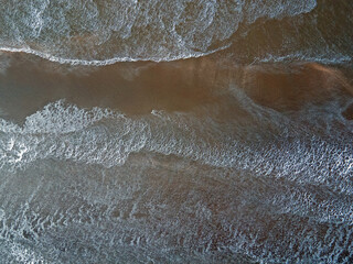 Aerial top down of waves and sea foam in IJmuiden beach and North Sea in North Holland