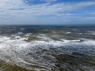 Aerial landscape of waves and sea foam in IJmuiden beach and North Sea in North Holland