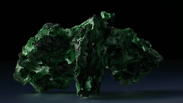Malachite [green copper carbonate hydroxide] Fibrous chatoyant form giving cat's eye effect sample rotating slowly against a black background.	