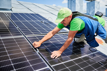 Worker building photovoltaic solar panel system on rooftop of house. Close up of man engineer...