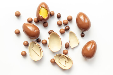 Chocolate eggs broken on white background. Chocolate sweets, top view