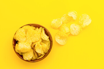 Wooden bowl of crispy potato chips, top view. Fast food and snack background