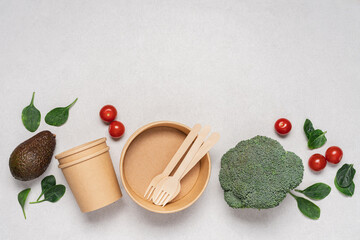 Disposable cardboard tableware on white background with broccoli, avocado, spinach and tomatoes....
