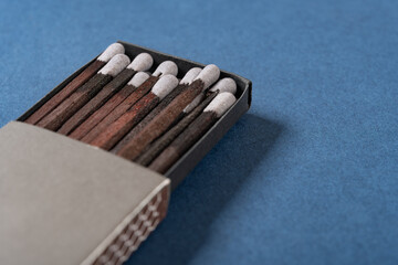 angle view grey color matchbox and grey match sticks on a blue background at horizontal composition