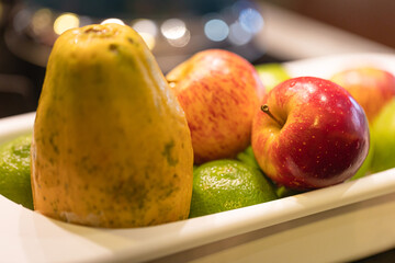 Um cesto plástico com frutas higienizadas com uma maçã vermelha em destaque.