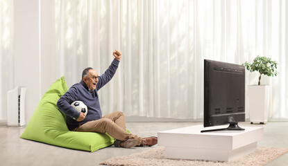 Mature man at home cheering and watching football