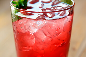 Strawberry cocktail with mint leaves and ice cubes in a glass glass close up