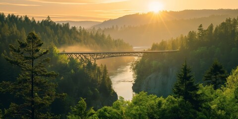 A majestic sunrise scene with soft sunbeams illuminating a bridge amidst forested mountains