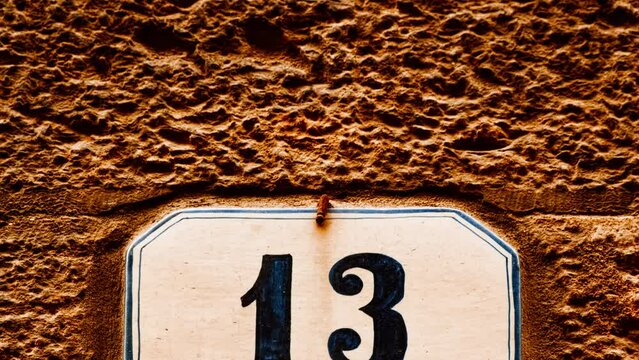 Number 13 (thirteen) affixed to the exterior of a building, with an elegant, vintage and traditional appearance