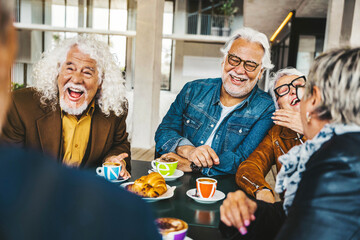 Happy senior people having breakfast sitting at cafe bar - Group of older friends having lunch at...