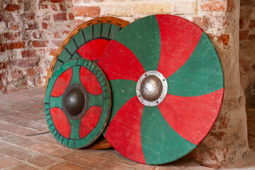 Ancient wooden shield with red and green colors on a brick wall background