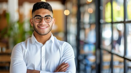 Obraz premium A man, wearing glasses and a white shirt, stands before a window with crossed arms and a smile