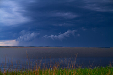 Dramatic stormy sky over the lake with grass in foreground