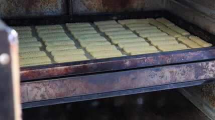 Baking Fresh Butter Cookies: Cookie Dough Extruded from a Press onto a Baking Sheet in Rows
