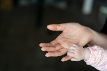 Baby hand holds little finger of cervix against dark background. Image with copy space