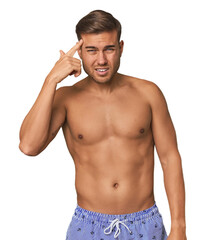 Fototapeta premium Young man shirtless in swimwear, studio showing a disappointment gesture with forefinger.