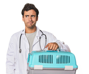 Young Hispanic man as vet with cage confused, feels doubtful and unsure.