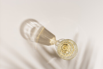 Top view of wineglass with white wine, palm leaf shadow and glare from glass at sunlight, summer...