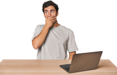 Hispanic young man working on laptop thoughtful looking to a copy space covering mouth with hand.