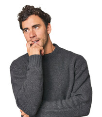 Young Hispanic man in studio relaxed thinking about something looking at a copy space.