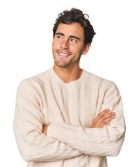 Young Hispanic man in studio smiling confident with crossed arms.
