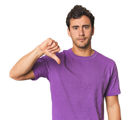 Young Hispanic man in studio showing a dislike gesture, thumbs down. Disagreement concept.