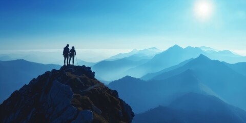 A tranquil image of two hikers on a summit witnessing the majesty of a mountain range highlighted by the soft light of sunrise