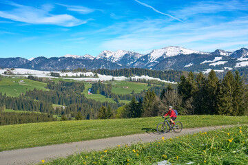 active senior woman riding her electric mountain bike on a sunny day in  spring with Dandelion...