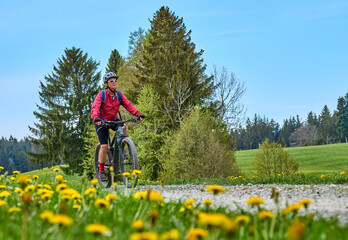 pretty senior woman riding her electric mountain bike in  springtime in the Allgau mountains near...