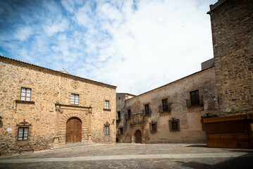 Fototapeta premium Vista panorámica del casco histórico de la ciudad española de Cáceres con vistas a los tejados de tejas marrones de edificios antiguos alrededor de la plaza principal en el soleado día de primavera