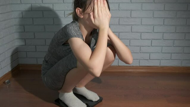 Girl frustrated over weight. A frustrated young girl stand on the scales in the room during diet time.