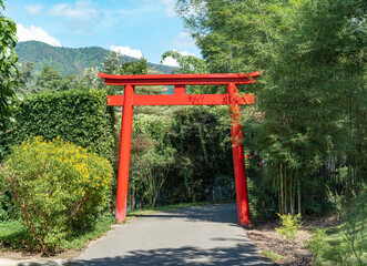 Single Japanese spiritual, traditional red pole with the bamboo tree and the Other tree  in the garden at noon time.
