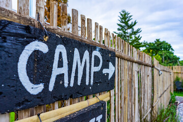 The black wooden sign with white letter label CAMP in front of the accommodation for direction...