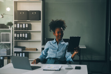 Happy excited successful Asian businesswoman triumphing with a laptop computer smartphone in the...